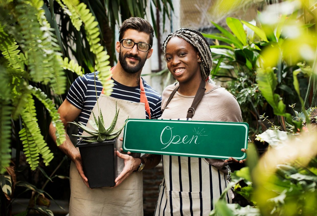Two smiling business owners in a greenhouse